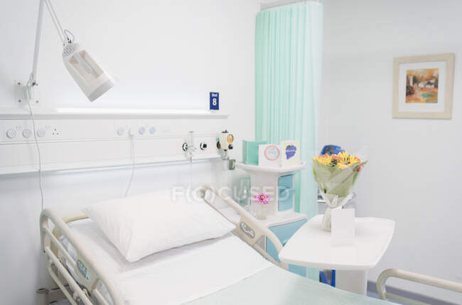 Flower bouquet and Get Well card on tray in vacant hospital room — Stock Photo