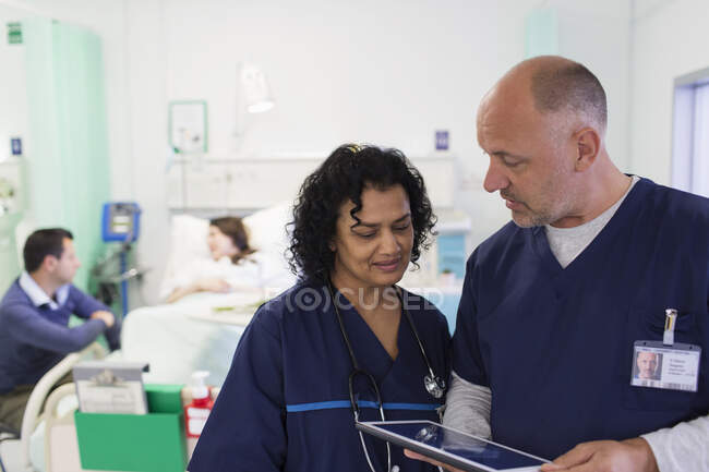 Doctors with digital tablet making rounds, consulting in hospital room — Stock Photo