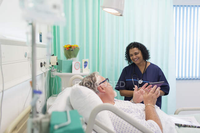 Medico sorridente che fa il giro, che parla con il paziente anziano nella stanza d'ospedale — Foto stock