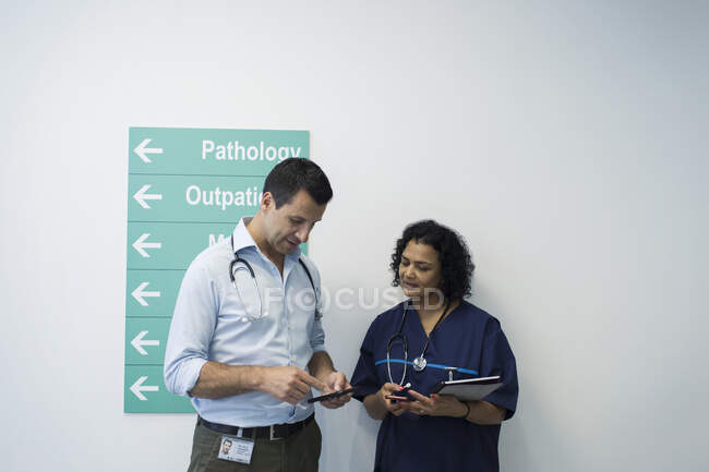 Ärzte mit Smartphones unterhalten sich auf Krankenhausflur — Stockfoto
