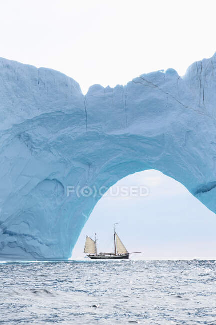 Ship sailing behind iceberg arch on Atlantic Ocean Greenland — Stock Photo
