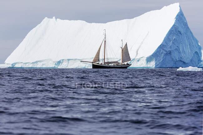 Barco navegando por el majestuoso iceberg en el soleado Océano Atlántico Groenlandia - foto de stock