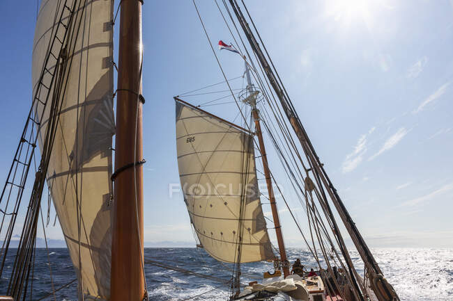 Wooden sailboat masts and sails under sunny blue sky Atlantic Ocean — Stock Photo
