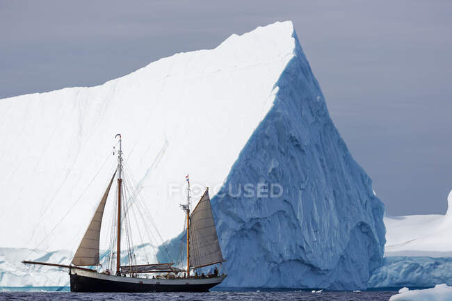 Navio navegando abaixo majestoso iceberg Oceano Atlântico Groenlândia — Fotografia de Stock