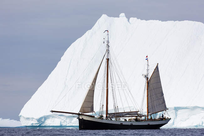 Navio passando por iceberg majestoso no ensolarado Oceano Atlântico Groenlândia — Fotografia de Stock