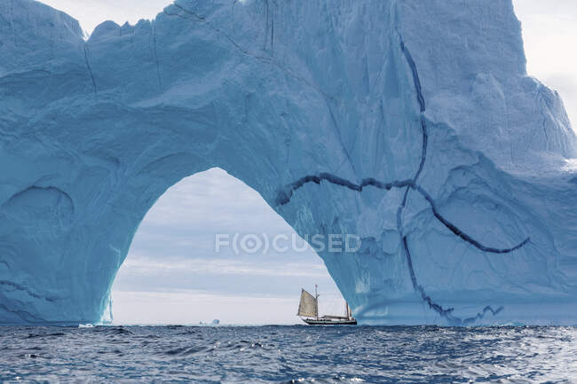 Barca a vela sotto maestoso arco iceberg Oceano Atlantico Groenlandia — Foto stock