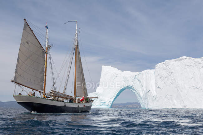 Nave che naviga con arco iceberg sulla soleggiata Groenlandia blu dell'Oceano Atlantico — Foto stock