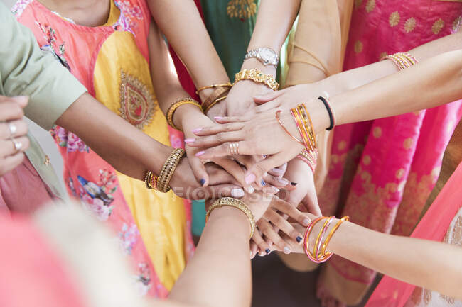 Indian women in bracelets joining hands in huddle — Stock Photo