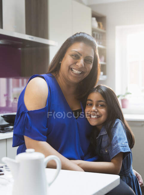 Portrait happy mother and daughter hugging in kitchen — Stock Photo