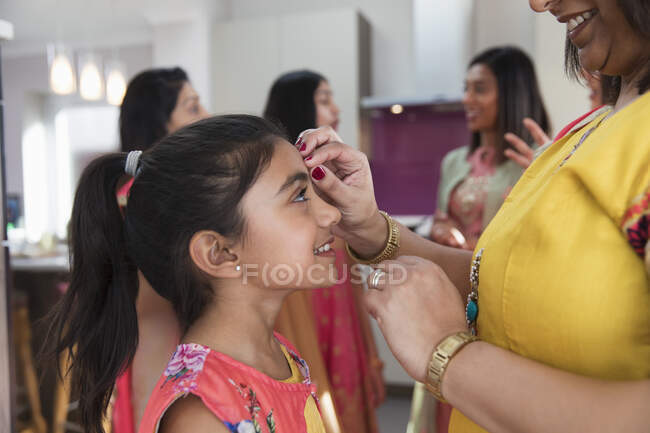 Mère indienne plaçant la liaison sur le front de la fille souriante — Photo de stock