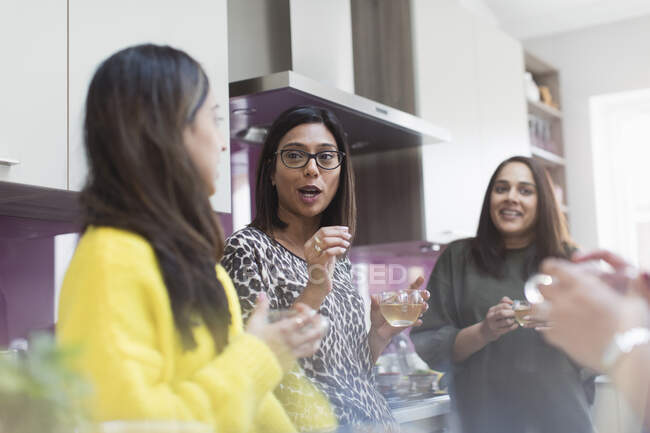 Women talking and drinking tea in kitchen — Stock Photo