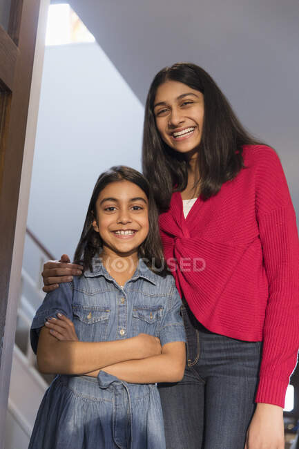 Retrato hermanas felices abrazándose en la puerta - foto de stock
