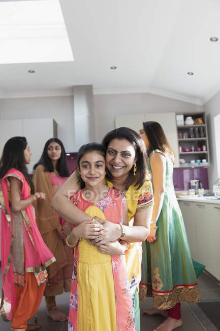 Retrato mãe indiana feliz e filha em saris abraçando na cozinha — Fotografia de Stock