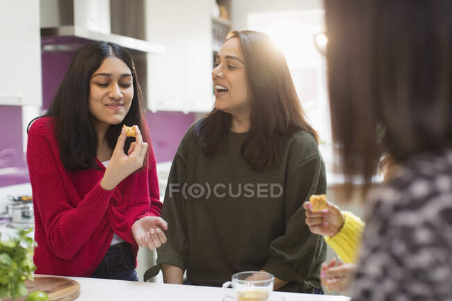 Mulheres felizes comendo e falando na cozinha — Fotografia de Stock