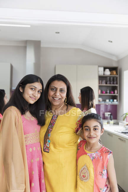 Портрет щасливої індійської матері та дочок у сарі на кухні — стокове фото
