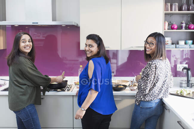 Retrato hermanas indias felices cocinando comida en la cocina - foto de stock