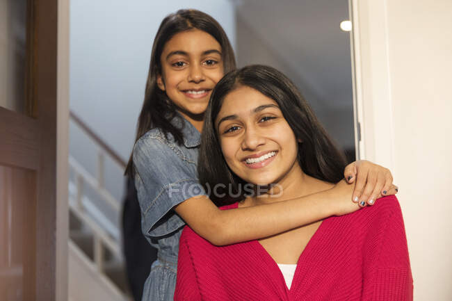 Portrait happy sisters hugging in doorway — Stock Photo