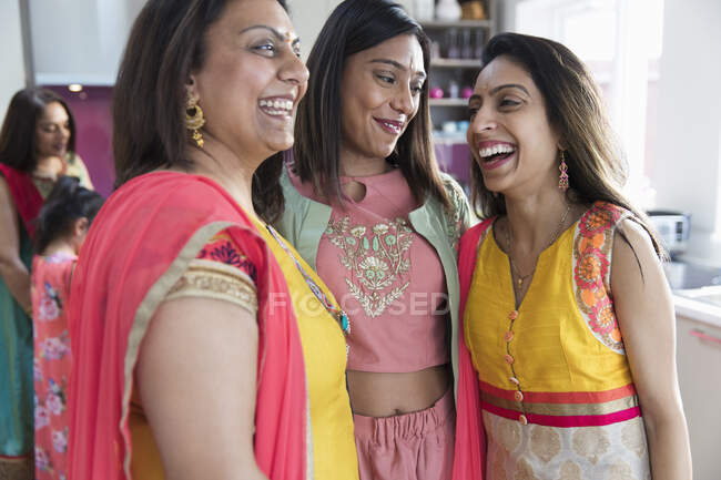 Щасливі індійські сестри в сарі сміються на кухні. — стокове фото