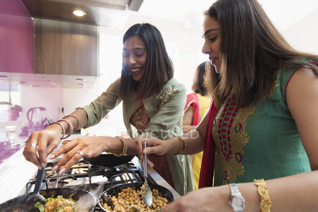 Mujeres indias en saris cocinando comida en la cocina - foto de stock