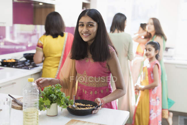 Portrait happy Indian girl in sari cooking food in kitchen — Stock Photo