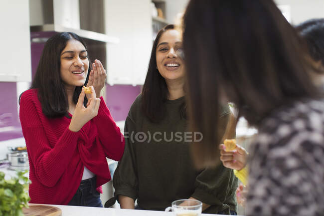 Mulheres felizes comendo e falando na cozinha — Fotografia de Stock
