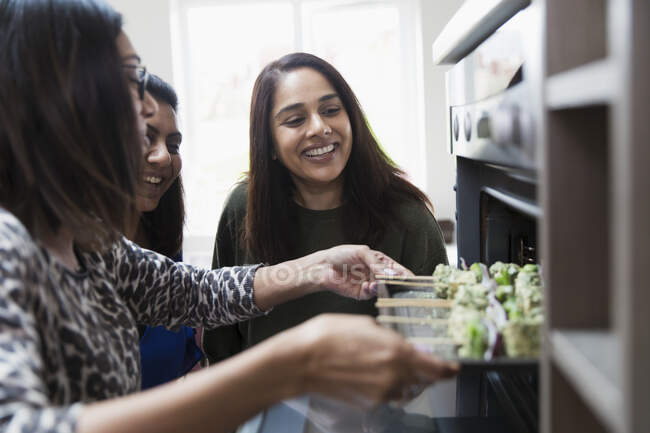 Indian women placing food in oven — Stock Photo
