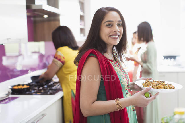Retrato mujer india feliz en sari cocina comida en la cocina - foto de stock