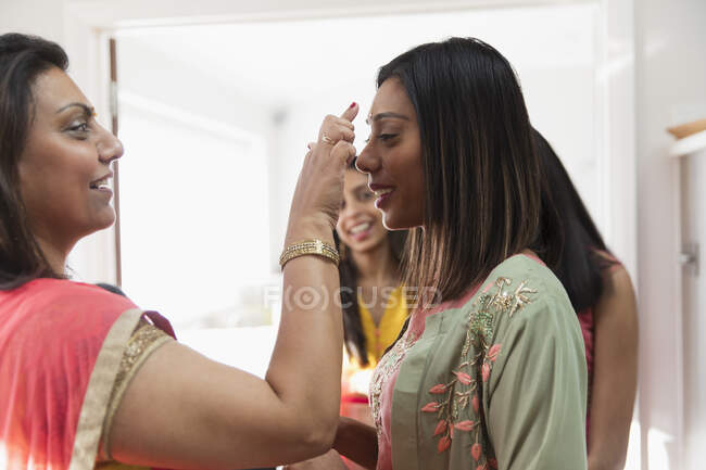 Mujer india colocando atadura en la frente de la hermana - foto de stock