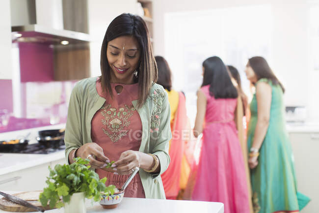 Mulher indiana em sari e ligar cozinhar alimentos com a família na cozinha — Fotografia de Stock