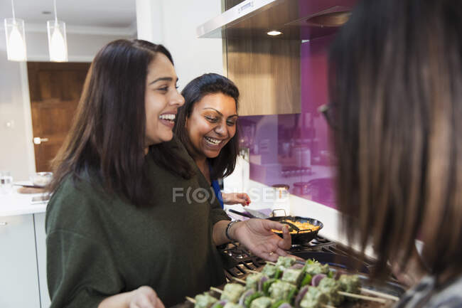 Happy Indian women preparing food in kitchen — Stock Photo