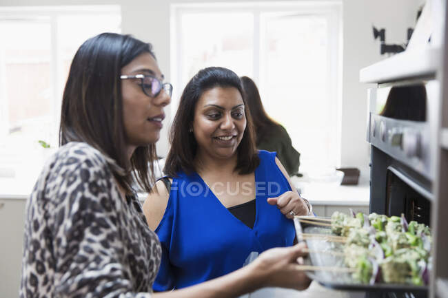 Mujeres indias colocando kebabs en el horno en la cocina - foto de stock