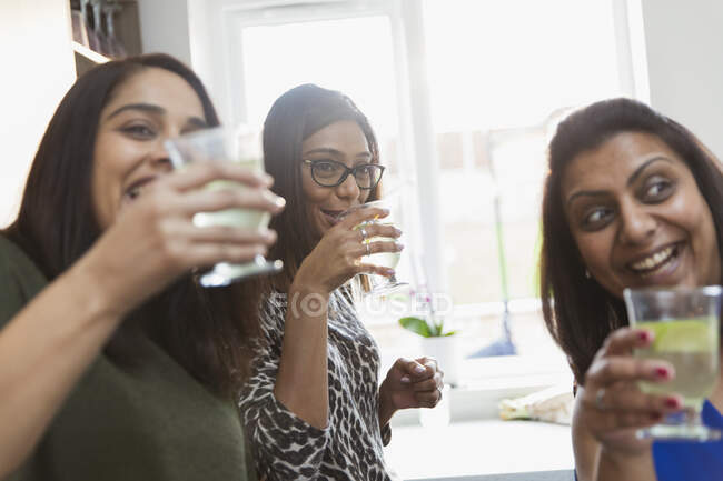 Happy Indian women drinking in kitchen — Stock Photo