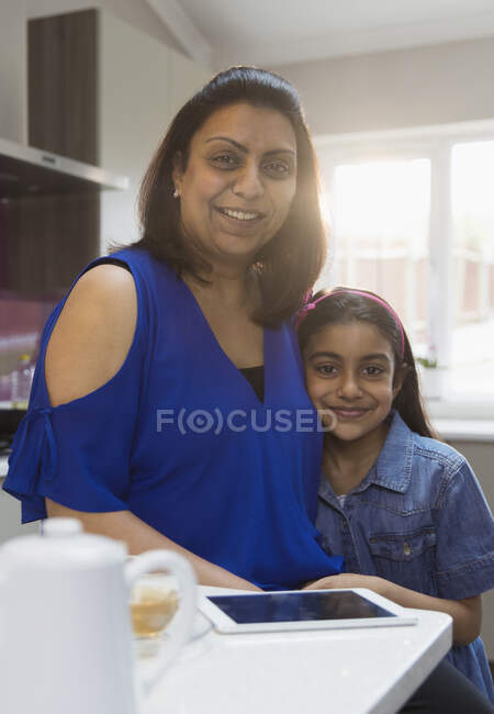 Портрет усміхненої матері і дочки з цифровим планшетом на кухні — стокове фото