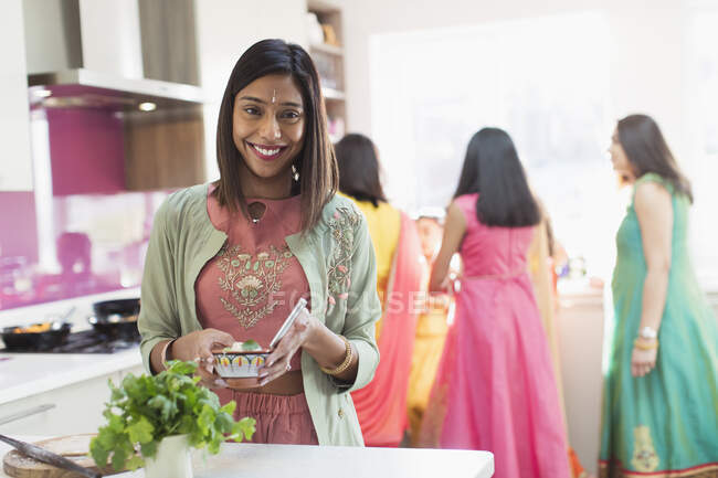 Portrait happy Indian woman in sari and bind cooking food in kitchen — Stock Photo