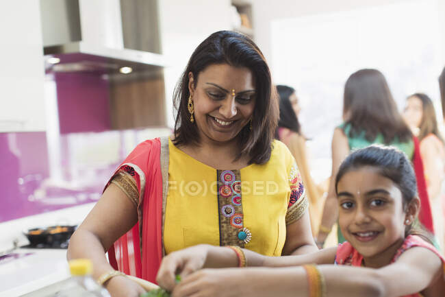 Індійська мати і дочка в сарі готують їжу на кухні. — стокове фото