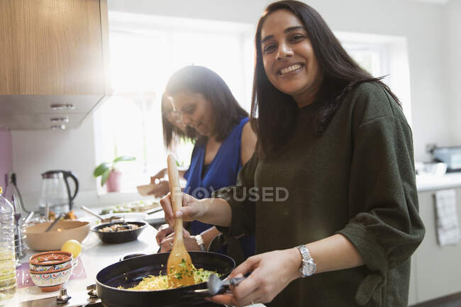 Portrait happy Indian woman cooking food at stove in kitchen — Stock Photo