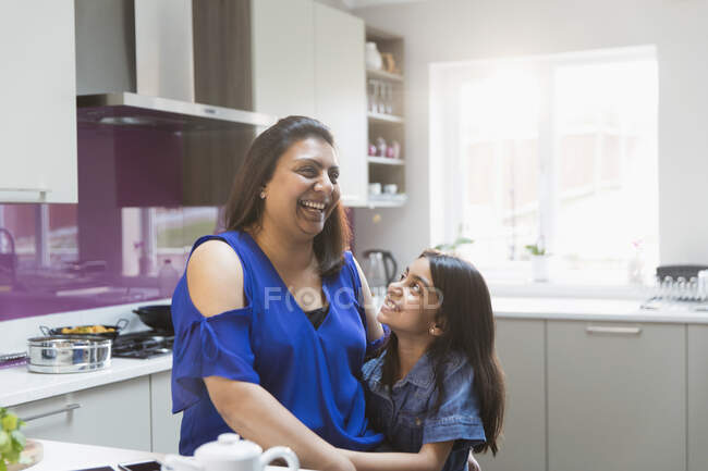 Felice madre e figlia abbracciare in cucina — Foto stock