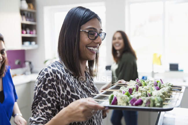 Happy Indian woman with tray of kebabs in kitchen — Stock Photo