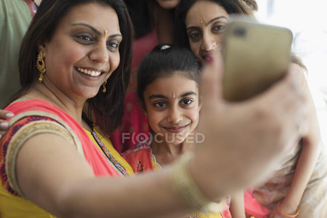 Happy Indian women in bindis and saris taking selfie with camera phone — Stock Photo