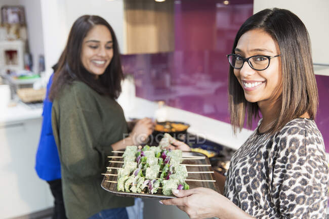 Portrait smiling Indian woman with tray of kebabs in kitchen — Stock Photo