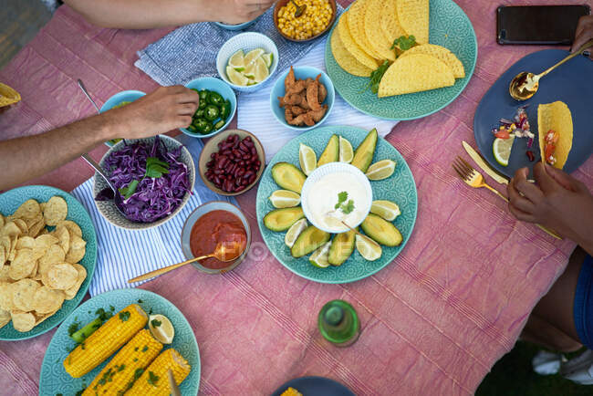 Conchas de tacos e ingredientes en la mesa del patio - foto de stock