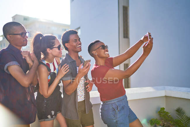 Счастливые молодые друзья делают селфи на солнечном городском балконе — стоковое фото