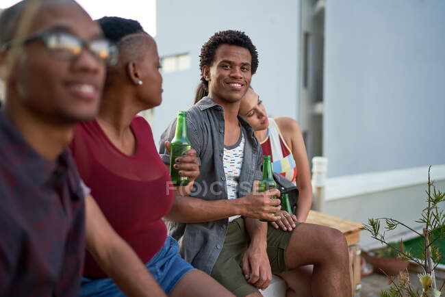 Portrait confident young man drinking beer with friends on patio — Stock Photo