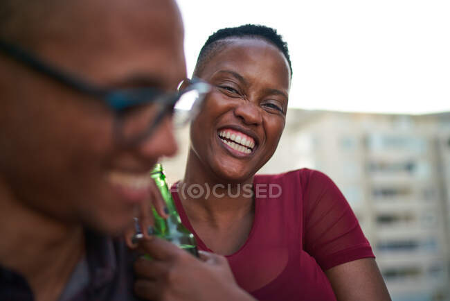 Portrait happy young woman drinking beer and laughing — Stock Photo