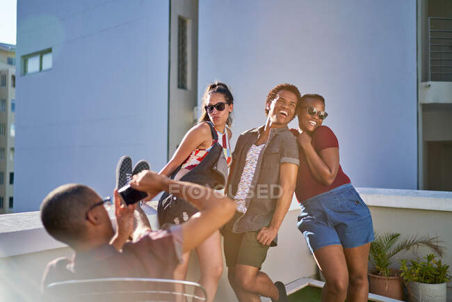 Giocoso giovani amici in posa per la foto sul balcone urbano soleggiato — Foto stock