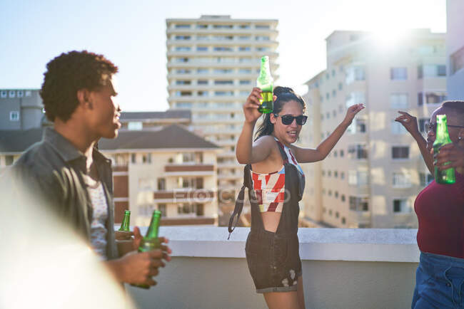 Jeunes amis insouciants dansant sur le balcon ensoleillé urbain sur le toit — Photo de stock