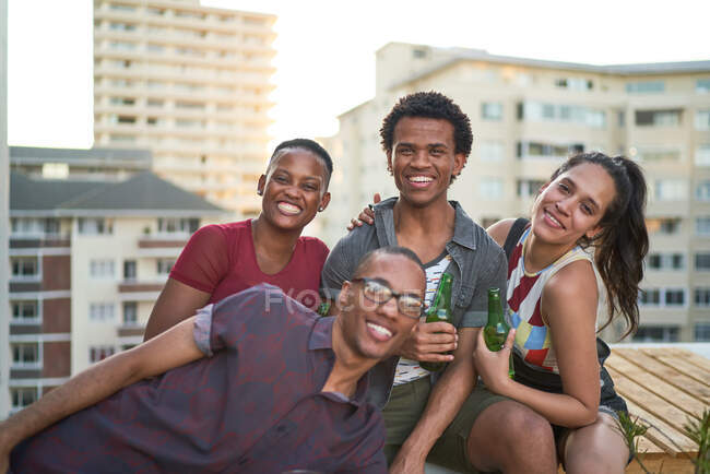 Portrait happy young friends hanging out on sunny urban rooftop — Stock Photo