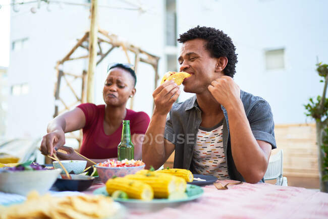 Giovane uomo mangiare taco pranzo al tavolo patio — Foto stock