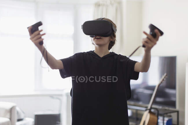 Мальчик играет в видеоигру с видеорегистраторами в гостиной — стоковое фото