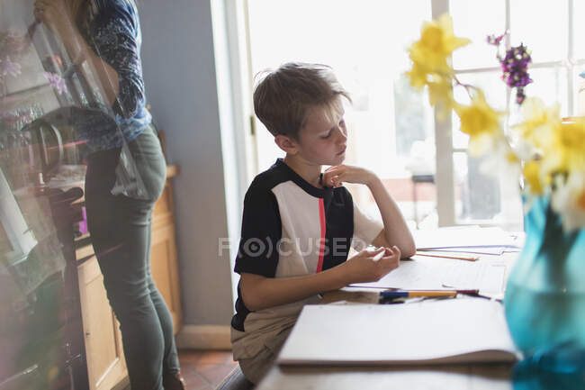 Хлопчик робить домашнє завдання за кухонним столом — стокове фото